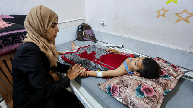 Palestinian boy Mohammed Imad, who was wounded in Israeli fire, is looked after by his mother as he lies on a bed at Al-Aqsa hospital in Deir Al-Balah in the central Gaza Strip 
