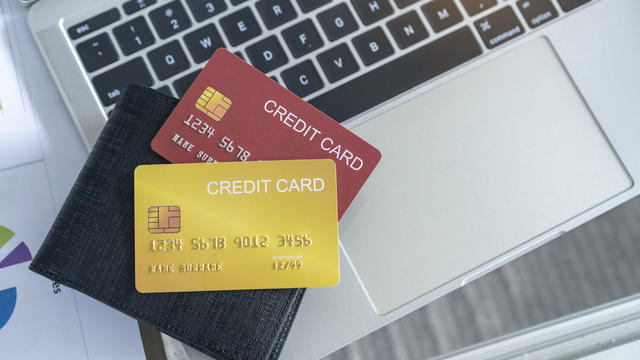 View of desk with credit card in the wallet on computer laptop. 