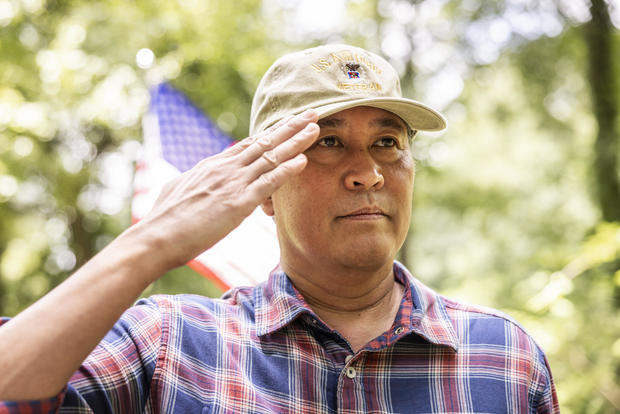 U.S. military veteran saluting in front of american flag 