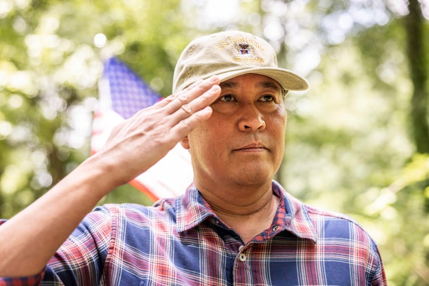 U.S. military veteran saluting in front of american flag