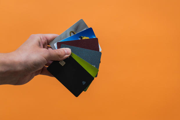Hand with a lot of credit cards with copy space on orange background 