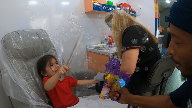 Health care providers use bubbles to distract a child during a blood test for lead 
