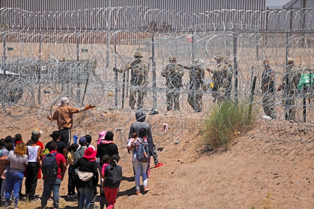Migrants seeking to enter the U.S. through a barbed-wire fence installed along the Rio Grande are driven away with pepper spray shots by Texas National Guard agents at the border with Ciudad Juárez, Mexico, on May 13, 2024.