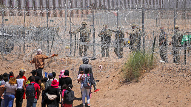 Migrants seeking to enter the U.S. through a barbed-wire fence installed along the Rio Grande are driven away with pepper spray shots by Texas National Guard agents at the border with Ciudad Juárez, Mexico, on May 13, 2024. 