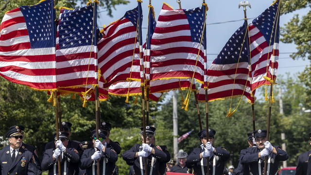 Members of Freeport (N.Y.) Fire Department holding American flags while marching in Memorial Day Parade 