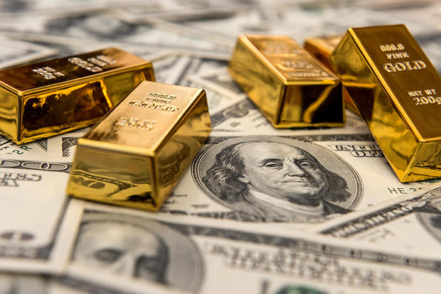 gold bars bullions lying on 100 dollar bills 