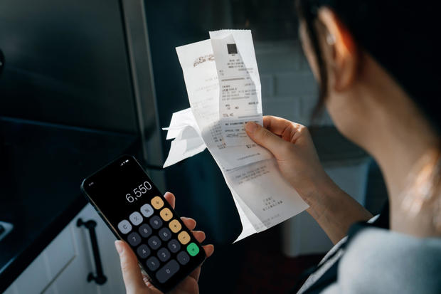 Young Asian woman calculating financial bills and receipts over kitchen counter, managing personal banking and finance. Planning budget and calculating expenses at home. Home budgeting. Home finances concept 