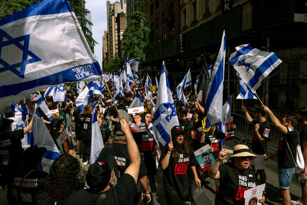 People, including families of hostages, walk through a sea of Israeli flags ahead of the Israel Day on Fifth parade on June 2, 2024 in New York City. 