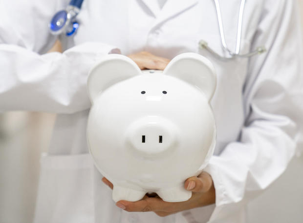 Doctor holding a piggybank at the hospital - health insurance 
