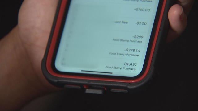 A cellphone screen shows multiple debits of hundreds of dollars from a person's SNAP account 