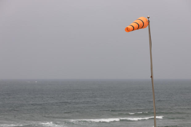 Bright orange windsock in a strong breeze at the ocean's edge 