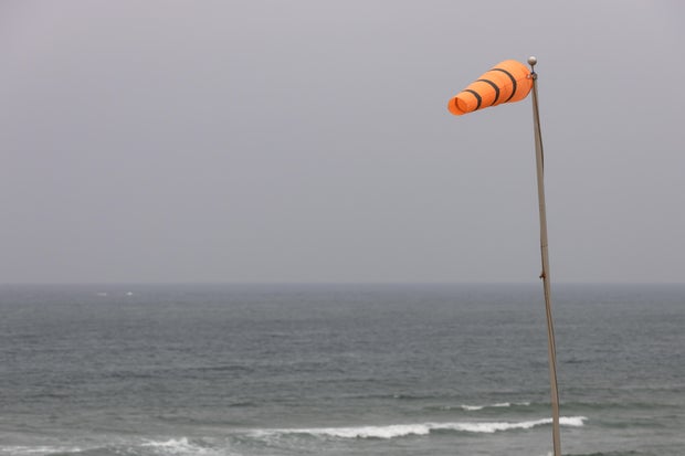 Bright orange windsock in a strong breeze by the ocean