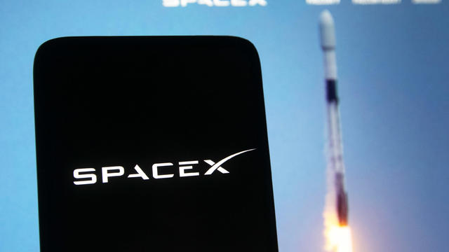 In this photo illustration a SpaceX logo seen displayed on a 