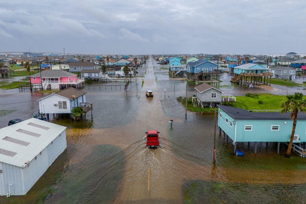 In this aerial image, vehicles drive through flooded neighborhoods on June 19, 2024 in Surfside Beach, Texas