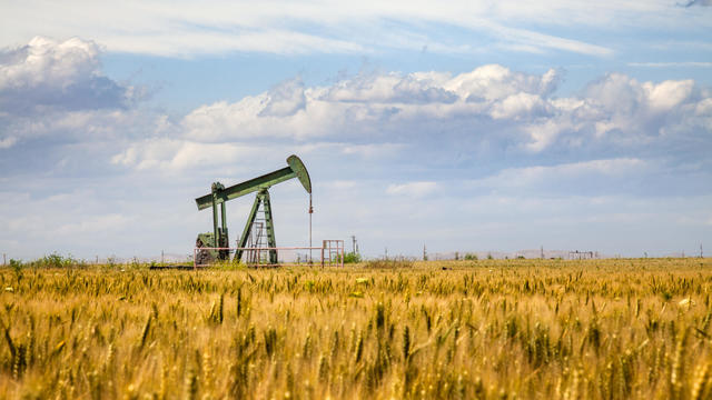 Lone Oil Pumpjack Amidst A Field of Golden Wheat 