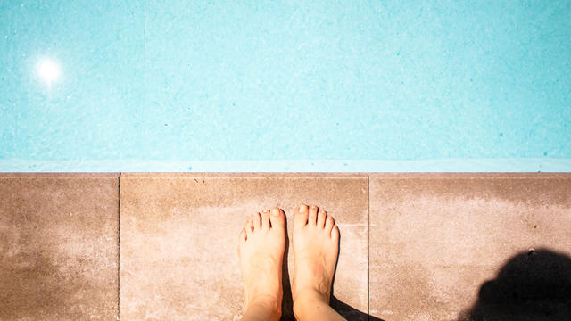 female legs and feet in blue swimming pool 