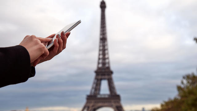 Girl using cellphone with Paris city background and Eiffel tower. 