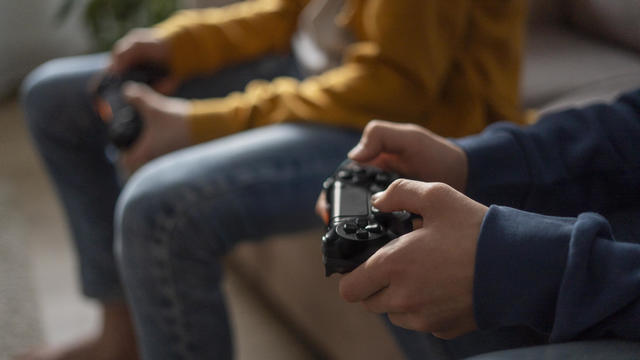 Hands of boys holding gaming consoles at home 
