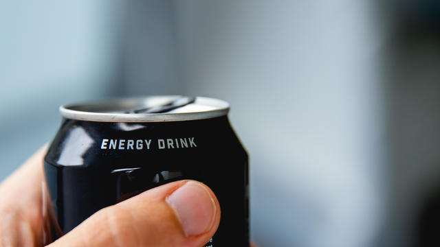 a close up of a hand holding a can of energy drink 