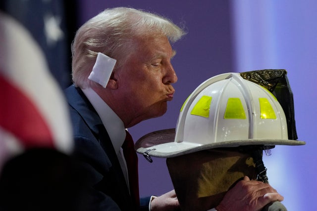 Former President Donald Trump kisses the helmet of Corey Comperatore during the Republican National Convention on Thursday, July 18, 2024, in Milwaukee. 