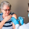 Older woman getting injected with a vaccine by doctor in upper arm. 