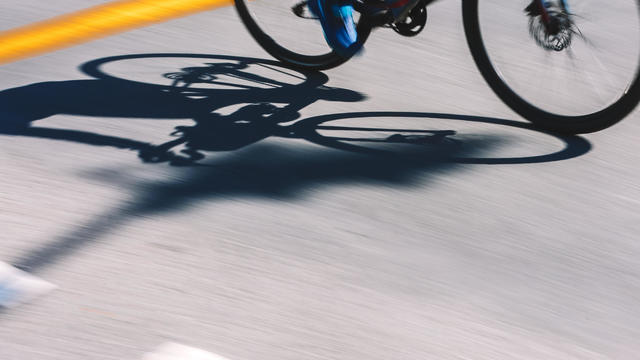 Abstract Sports Background. Light And Shadows Cyclist Silhouette At The Asphalt Road Background 
