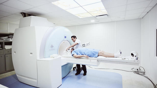 Male nurse preparing patient for MRI in hospital 
