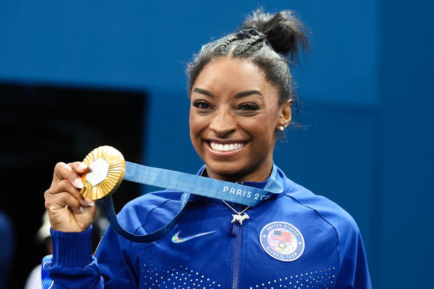 Simone Biles of Team USA shows off her gold medal 