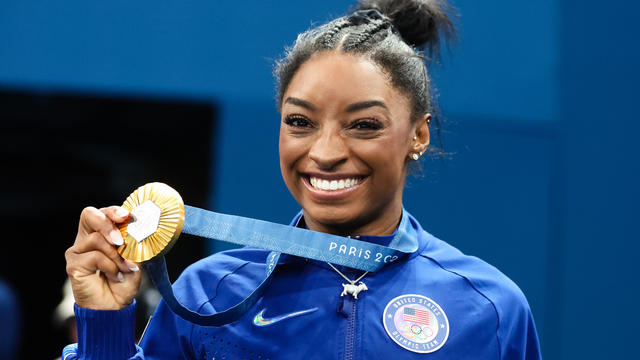 Simone Biles of Team USA shows off her gold medal 