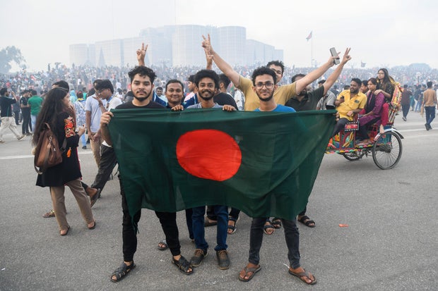Manifestantes antigovernamentais seguram a bandeira de Bangladesh no