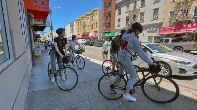 Cyclists ride on an SF Chinatown sidewalk 