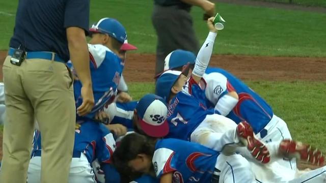 Members of the Staten Island Little League pile on top of one another on the ground in celebration of their victory. 