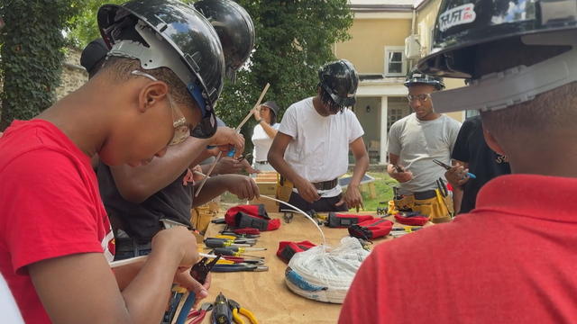 A group of teens work with tools during a camp 