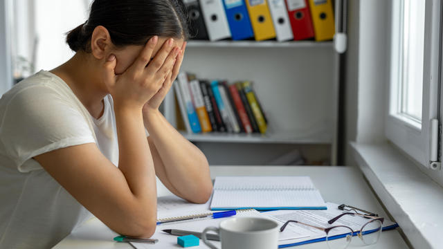 University student sadeness alone while sitting on table doing homework 