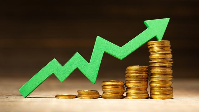 Green arrow graphic upward and stack of coins in steps upward as a symbol of success 