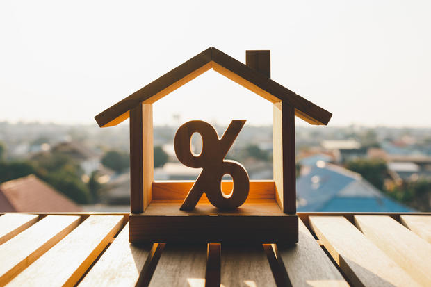 Percentage and house sign symbol icon wooden on wood table. Concepts of home interest, real estate, investing in inflation. 