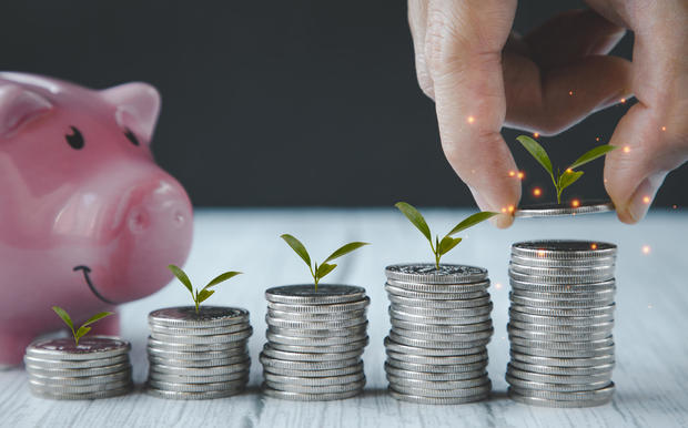 Close up of male hand stacking coins and Trees growing on coin in dark background ,Business Finance and Money, plant growing up on coins and investment budget, saving money investment.concept 