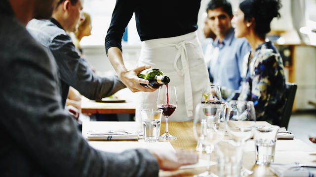 Waitress pouring wine into glass at table 