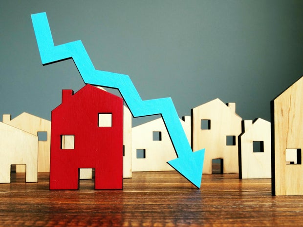 The crisis in the real estate market. Falling home value. Property and downward arrow.