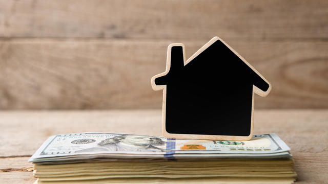 Dollar bills, blank blackboard in the shape of a house 