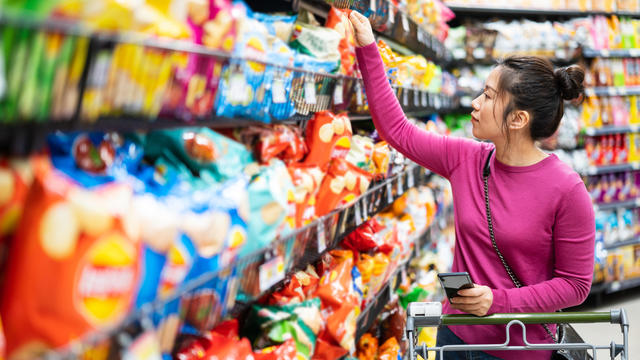 woman shopping in supermarket snack food aisle 