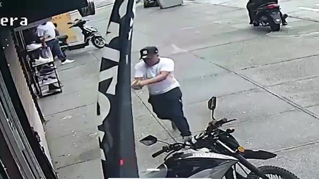 A man holding a gun on the sidewalk outside a Bronx barbershop. 