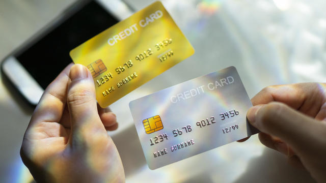 Close up Hand holding Blank credit card  black,gold,platinum color with spectrum light and shadow background 