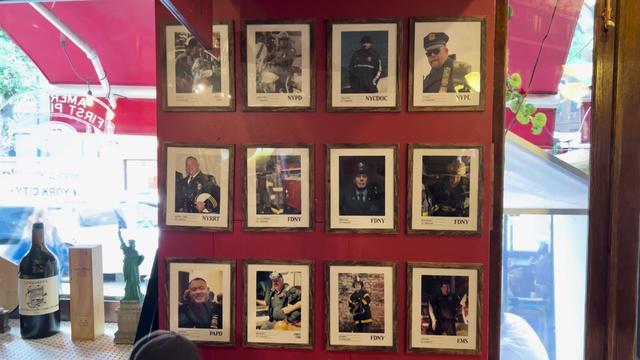 12 framed photos of 9/11 first responders hanging on a wall of a New York City pizzeria. 