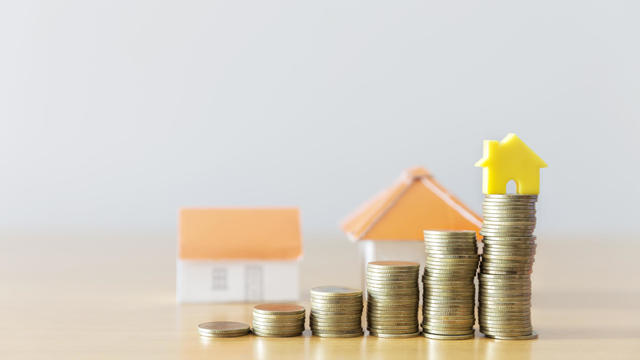 golden coins with house icon on wooden table with bokeh green background for growth up saving to buy house, mortgage or home loan concept 