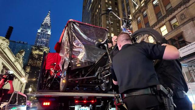 Two NYPD officers load a pedicab onto a tow truck. 