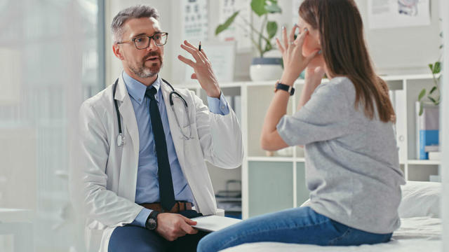 Shot of a mature doctor sitting with his patient in the clinic and asking questions during a consultation 