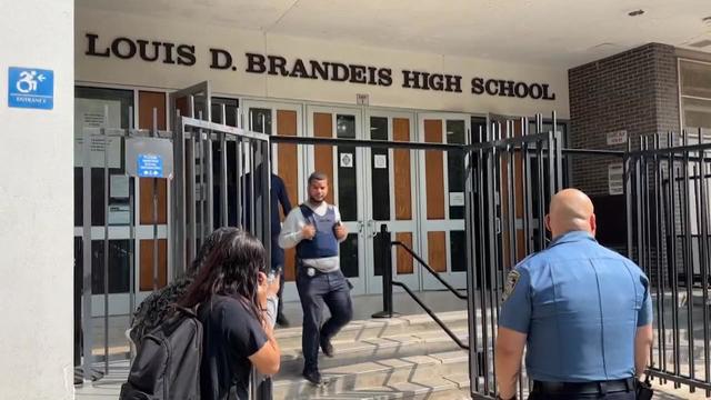 NYPD officers walk outside Louis D. Brandeis High School. 