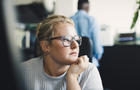 Female entrepreneur with hand on chin looking away in office 