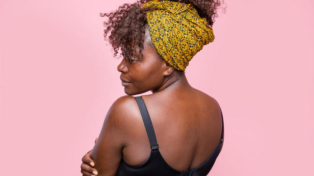 Confident black woman posing showing her back on pink background 